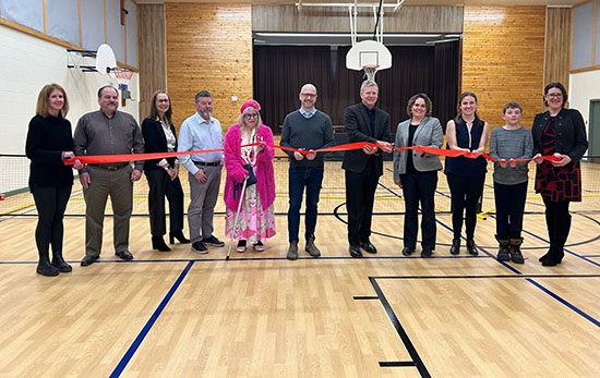 Image of a group cutting a red ribbon in a gym